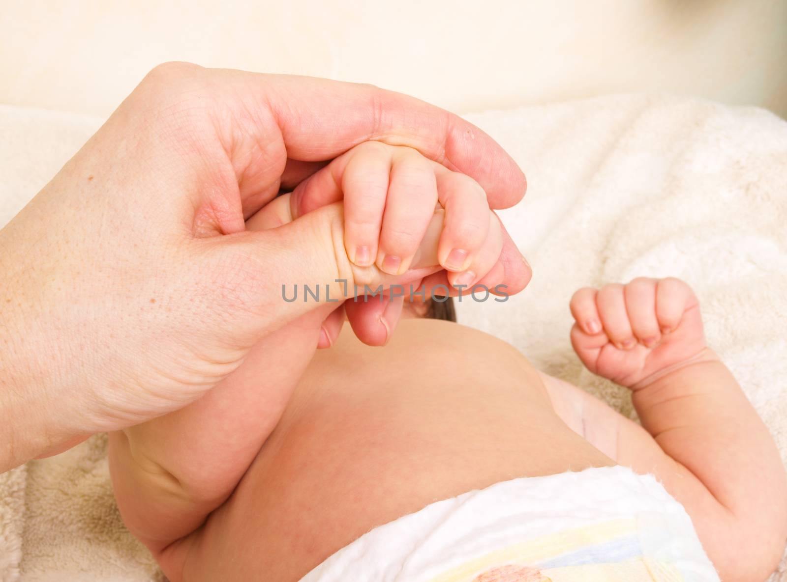 Newborn baby holding onto finger of parent after new diaper