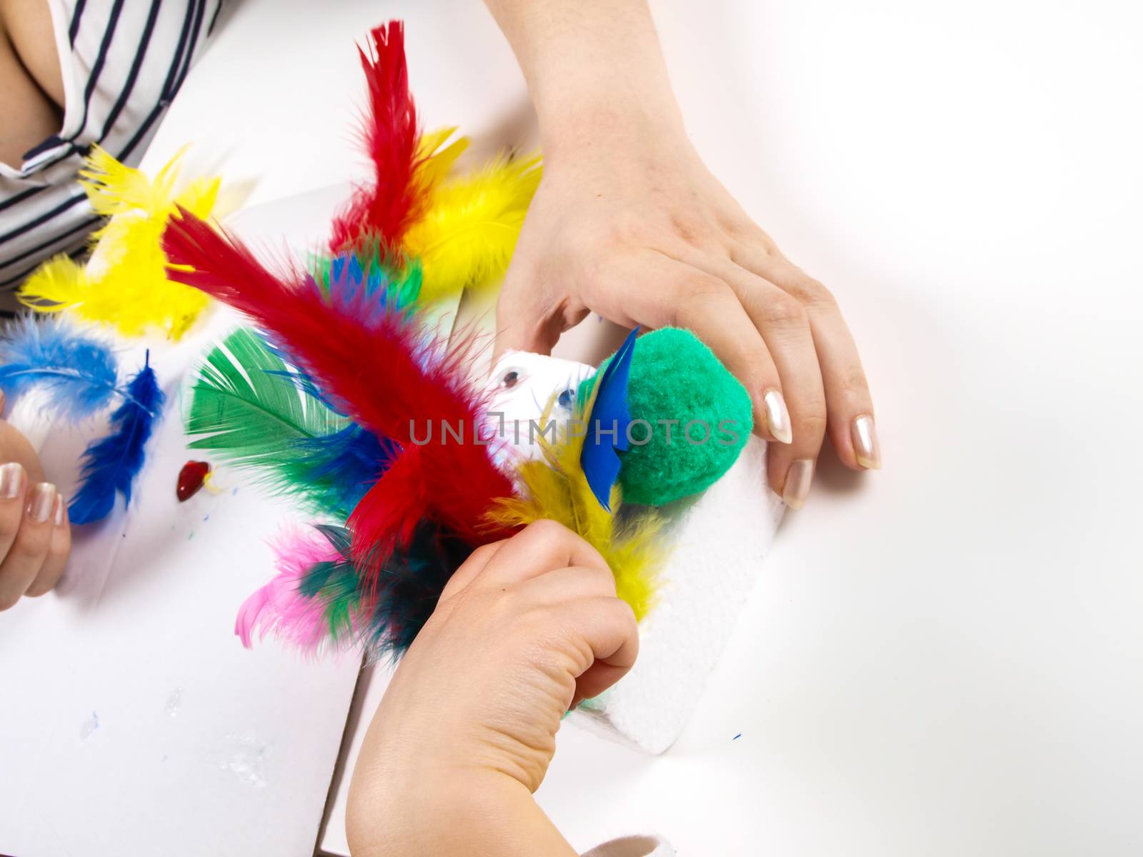 Little girls hands playing with colorful feathers, creating Easter decoration