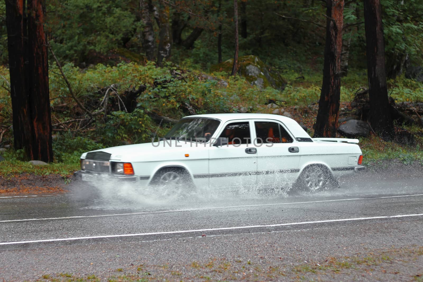 Automobile driving on the puddle on a highway