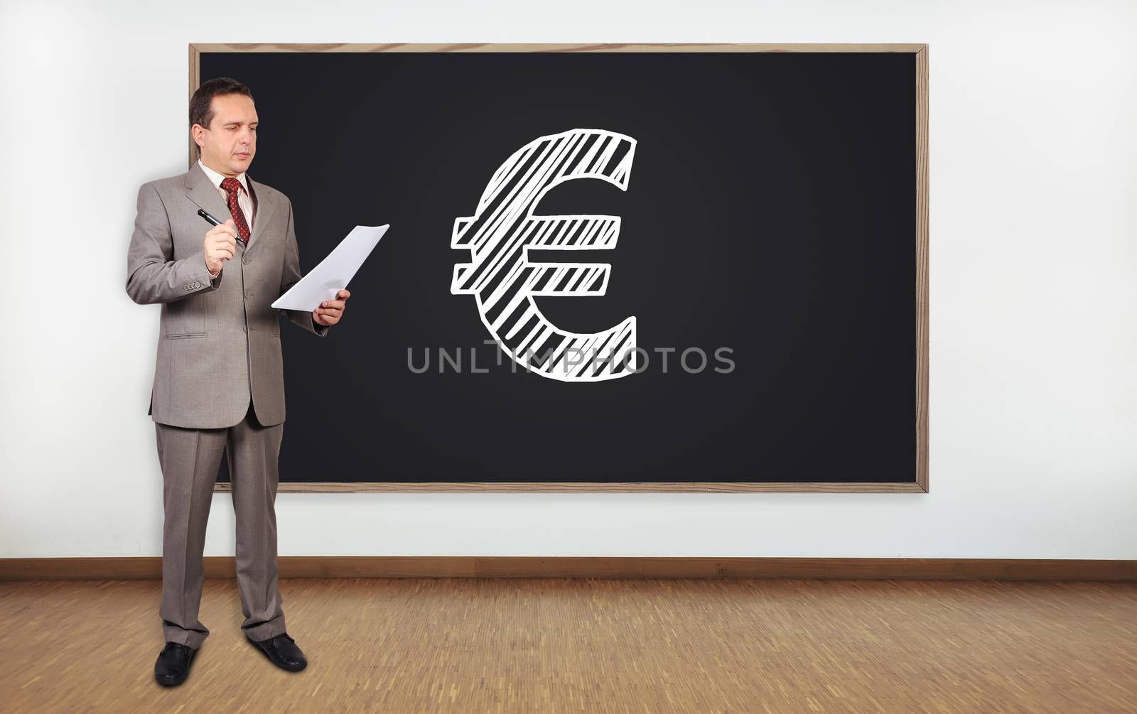 businessman standing in office and drawing euro symbol on  blackboard