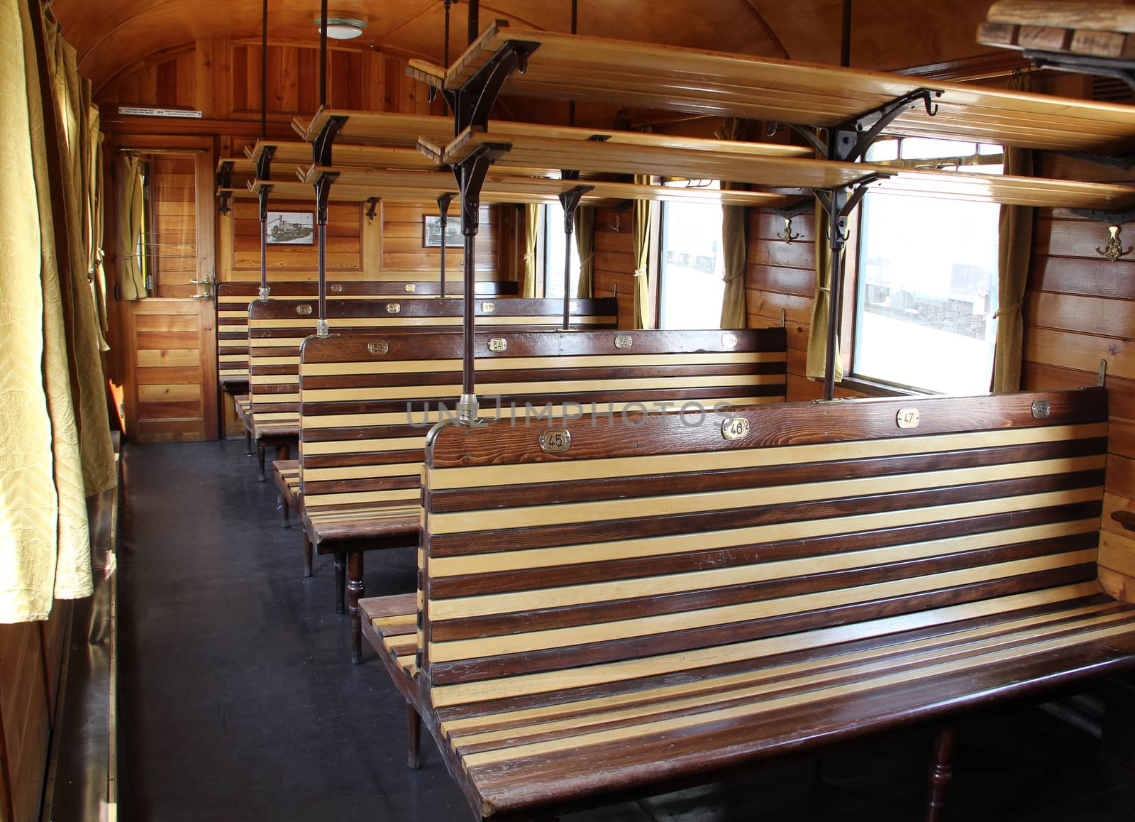 Old empty wooden benches inside the railway carriage.