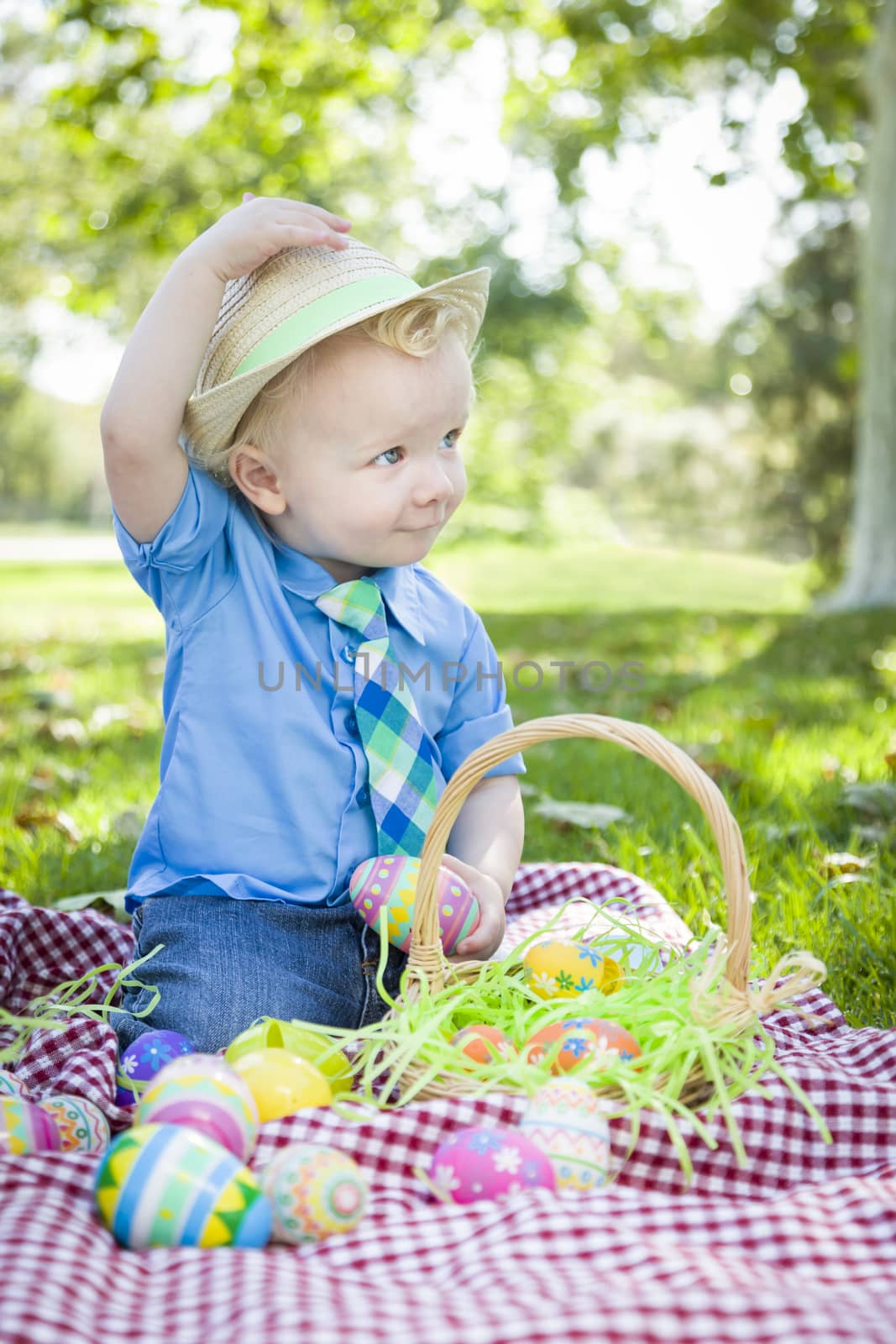 Cute Little Boy Outside On Picnic Blanket Holding Easter Eggs Tips His Hat.