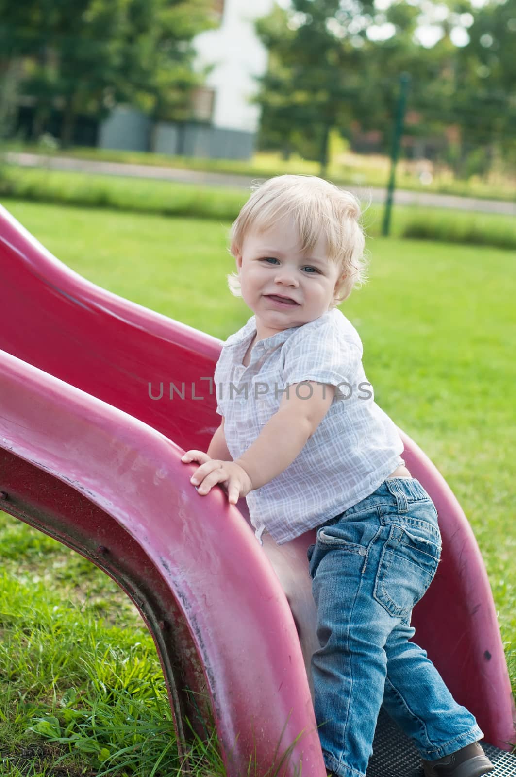 Smiling child playing on a baby slide outdoors