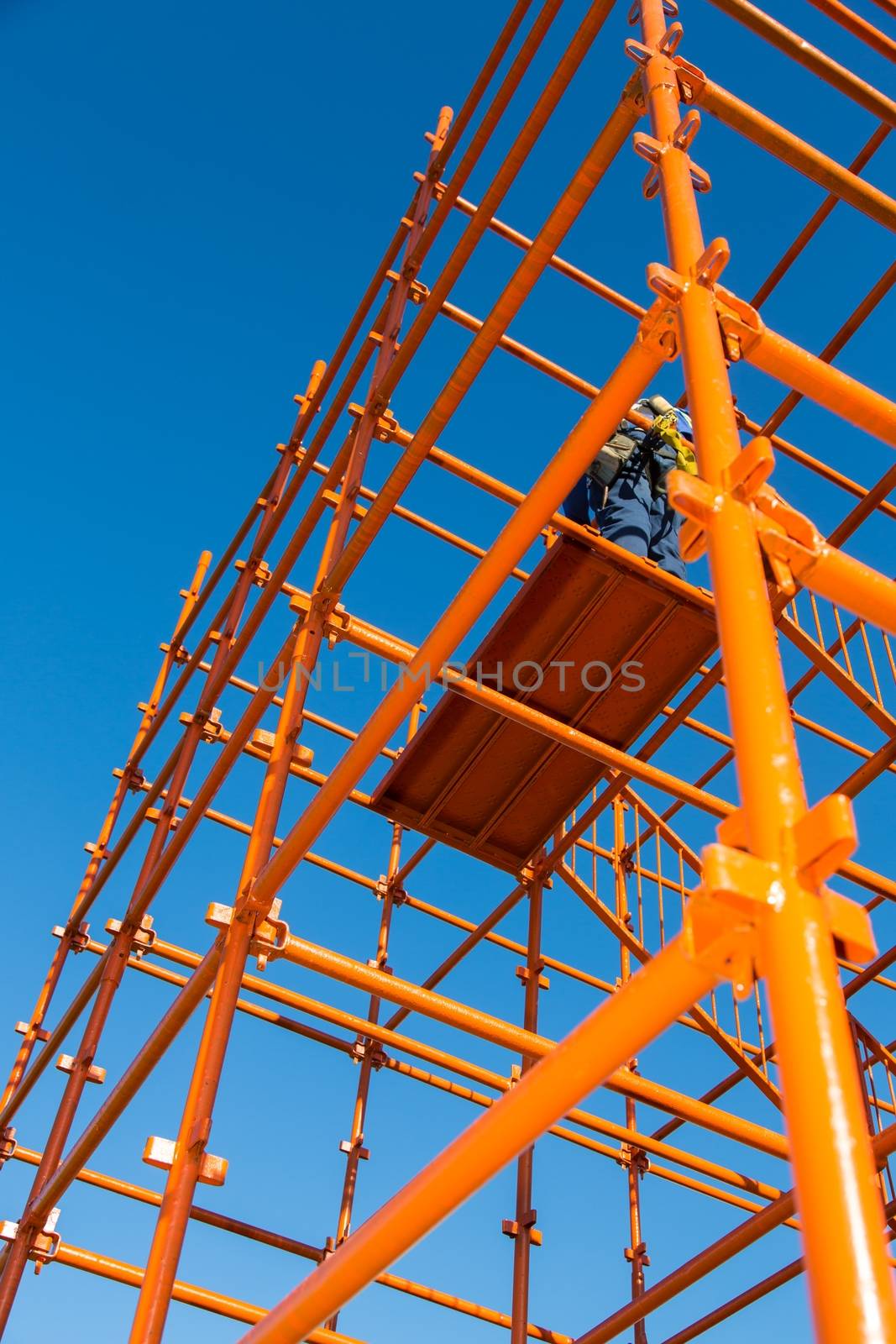 Bright orange scaffolding pipes against a blue sky