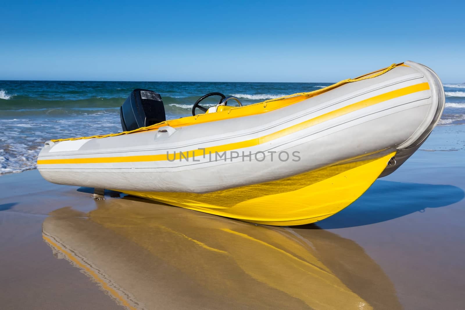 Yellow and white rubber duck inflatable boat on the sandy beach