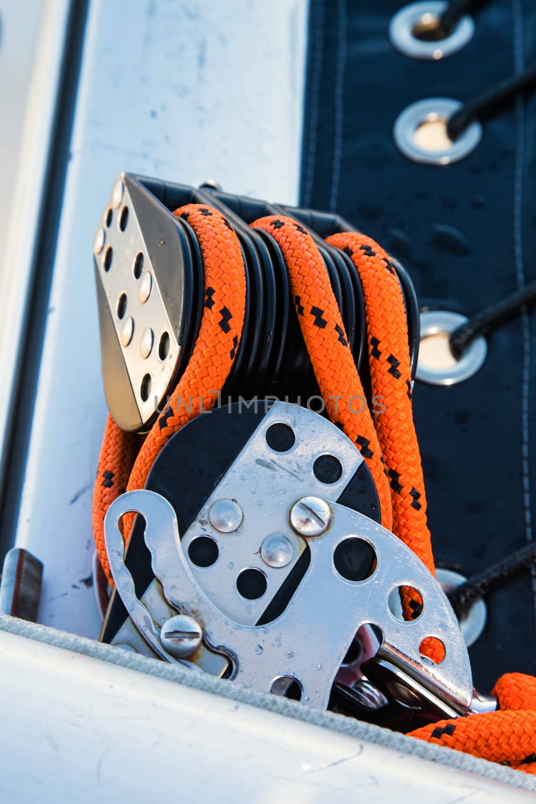 Pulleys with orange roaps and stainless steel buckles on a sailing yacht