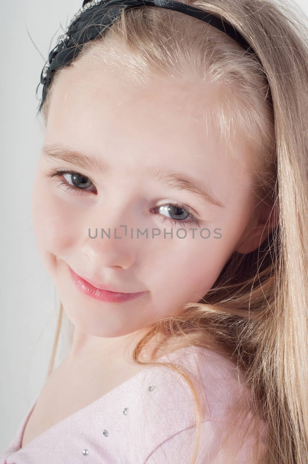 Happy little blond girl in studio watching on you