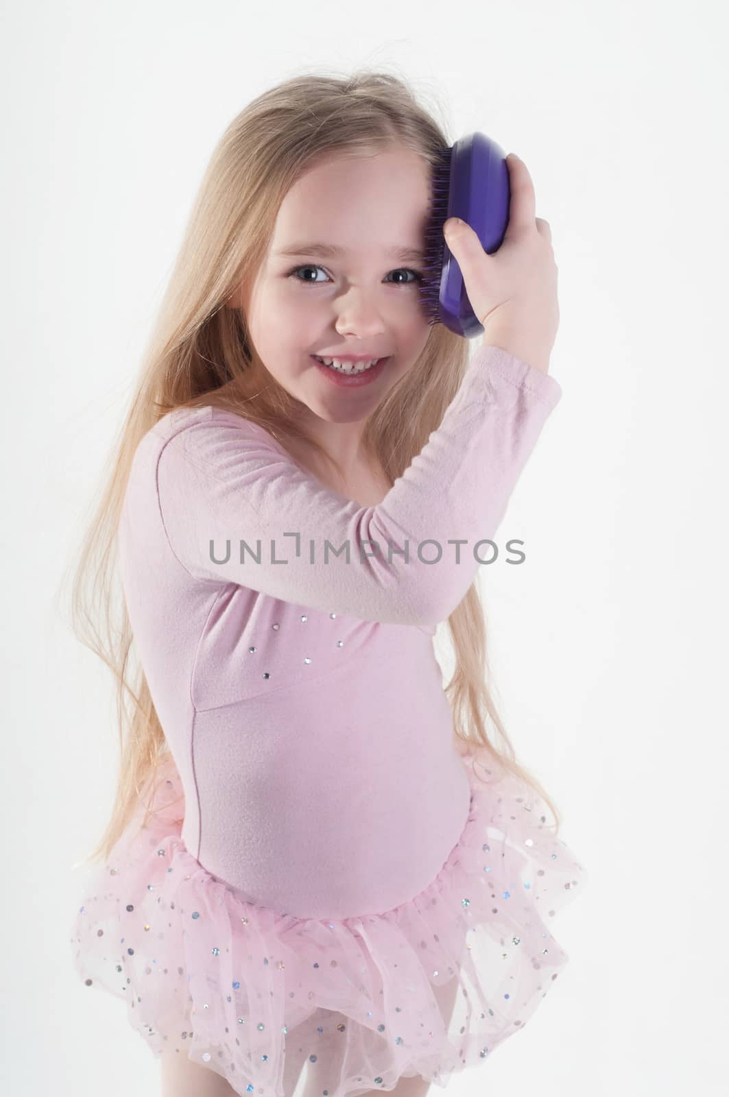 Little girl combing long blond hair in studio