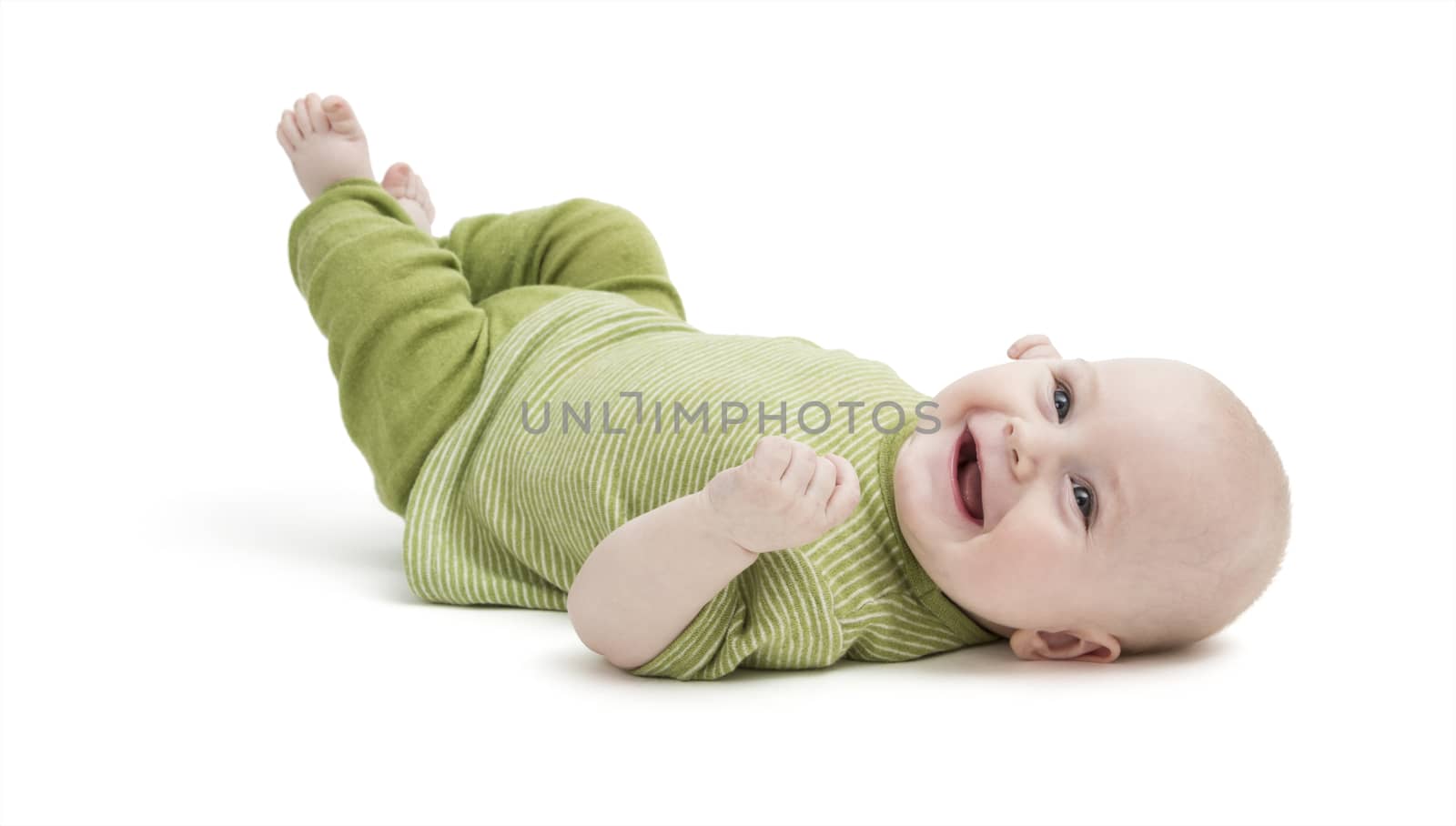 happy baby in green clothing lying on his back. isolated on white background