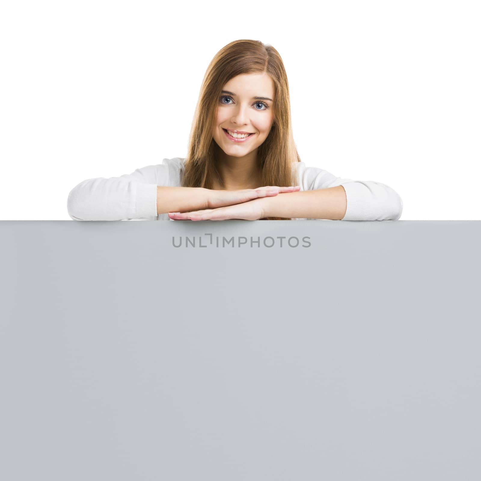 Young smiling woman leaning on a big blank board, isolated over white background