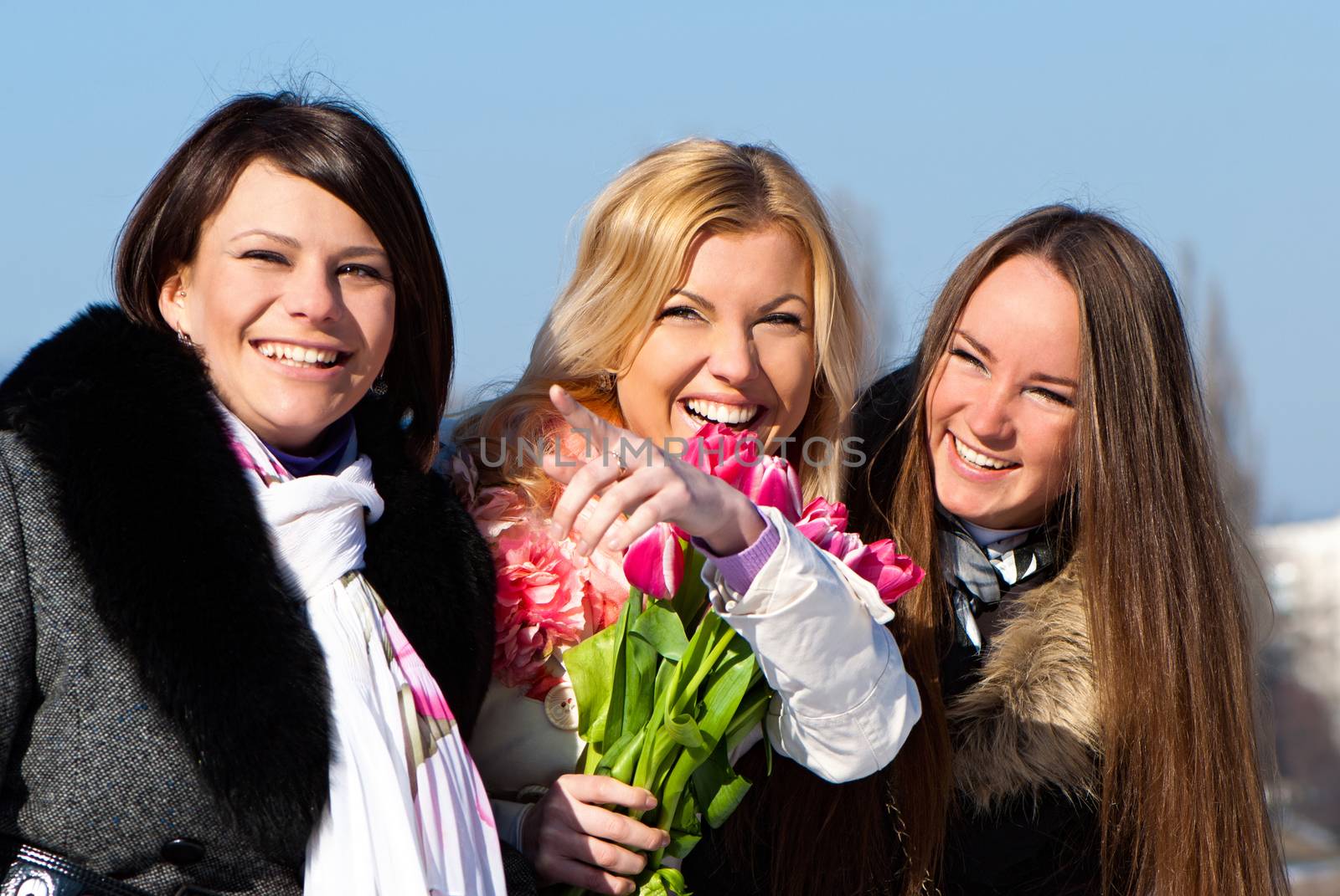 Three beautiful young women with pink tulips
