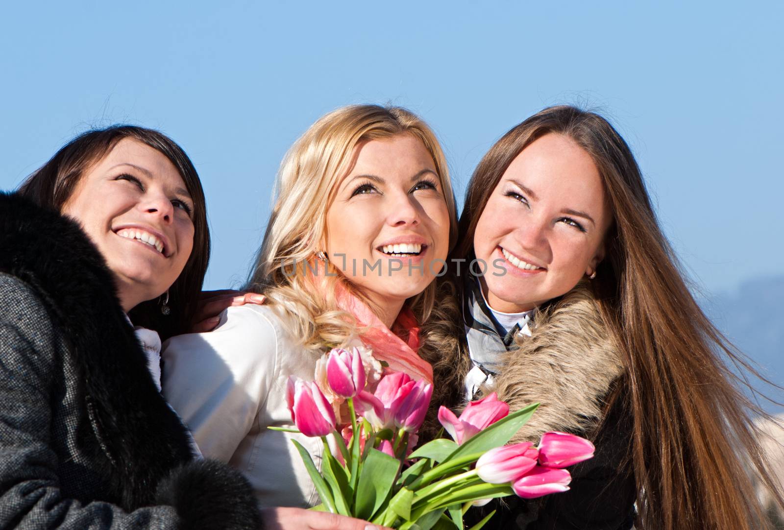 Happy three beautiful young women with pink tulips