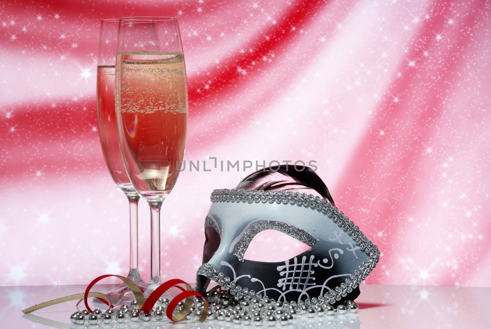 Glasses with champagne and venetian mask on an abstract background