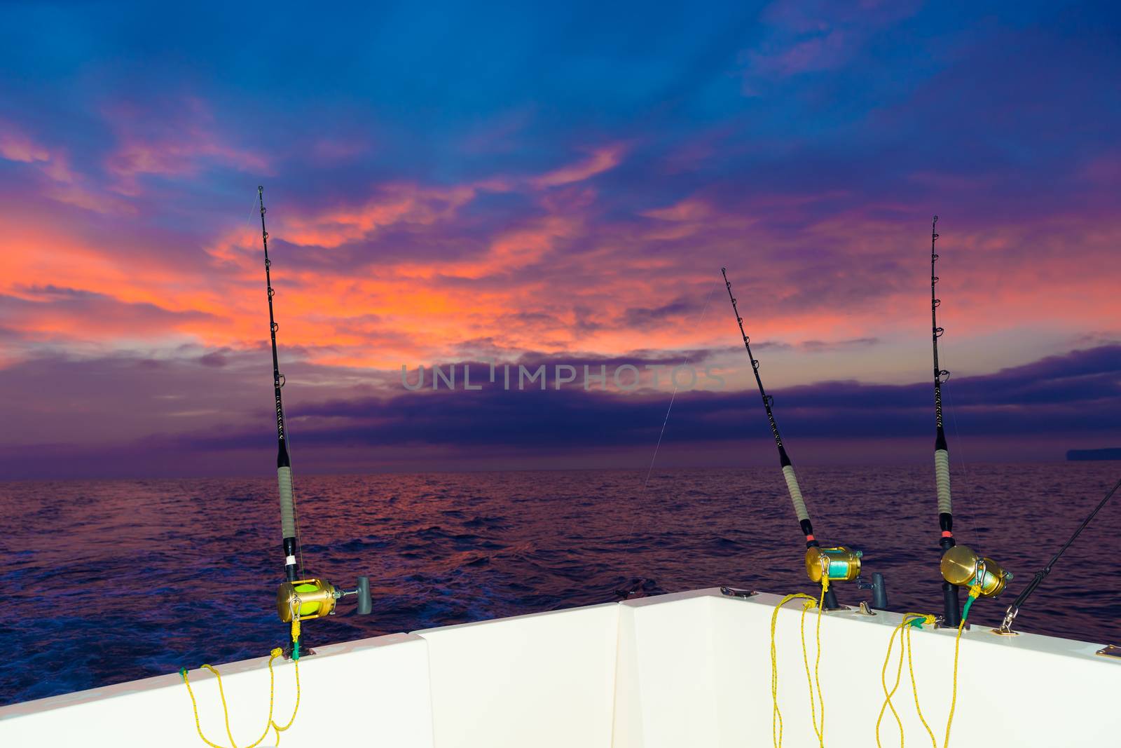boat fishing trolling at sunset with rods and reels by lunamarina