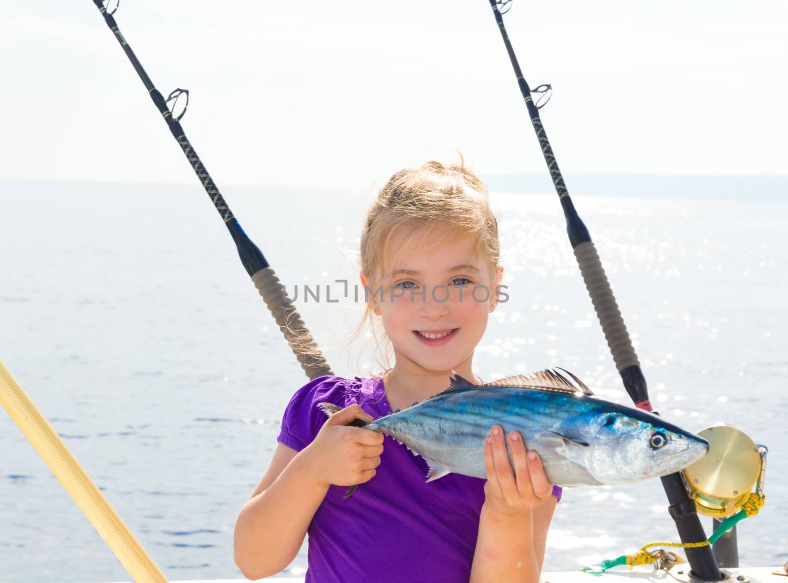 Blond girl fishing bonito Sarda tuna trolling in sea by lunamarina