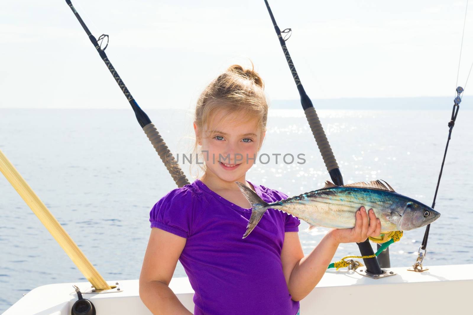 Blond girl fishing bonito Sarda tuna trolling in Mediterranean sea