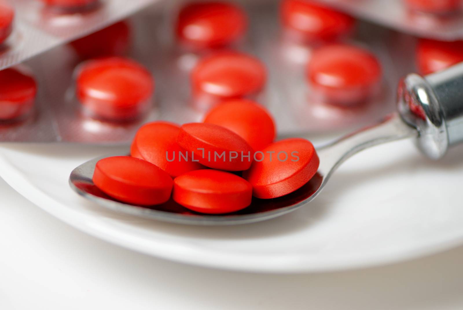 Closeup view of red tablets in silver spoon 