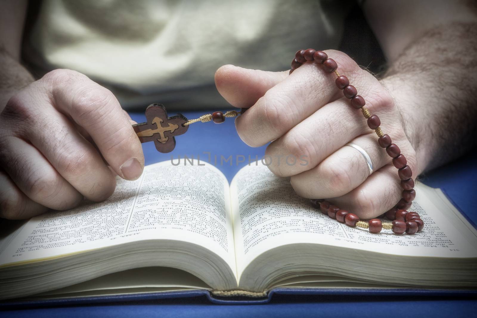 Christian believer praying to God with rosary in hand by digicomphoto