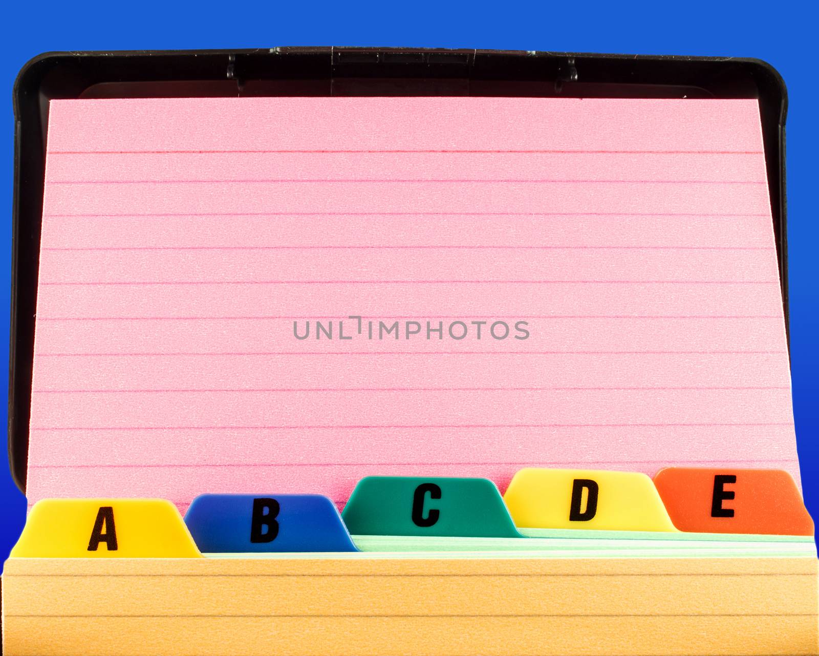 Close shot of a blank pink index card propped up against file box tabs. The background is a rich blue.