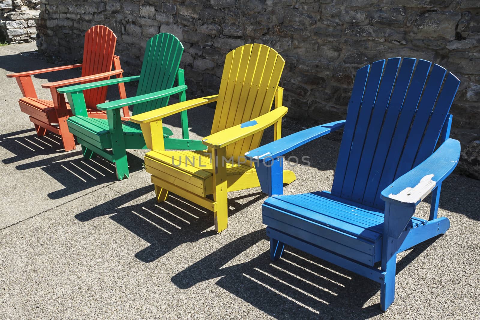 Row of colored adirondack chairs at high noon.
