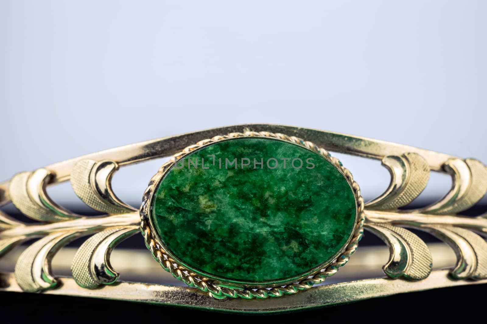 Green gemstone set inside a shiny gold band. 