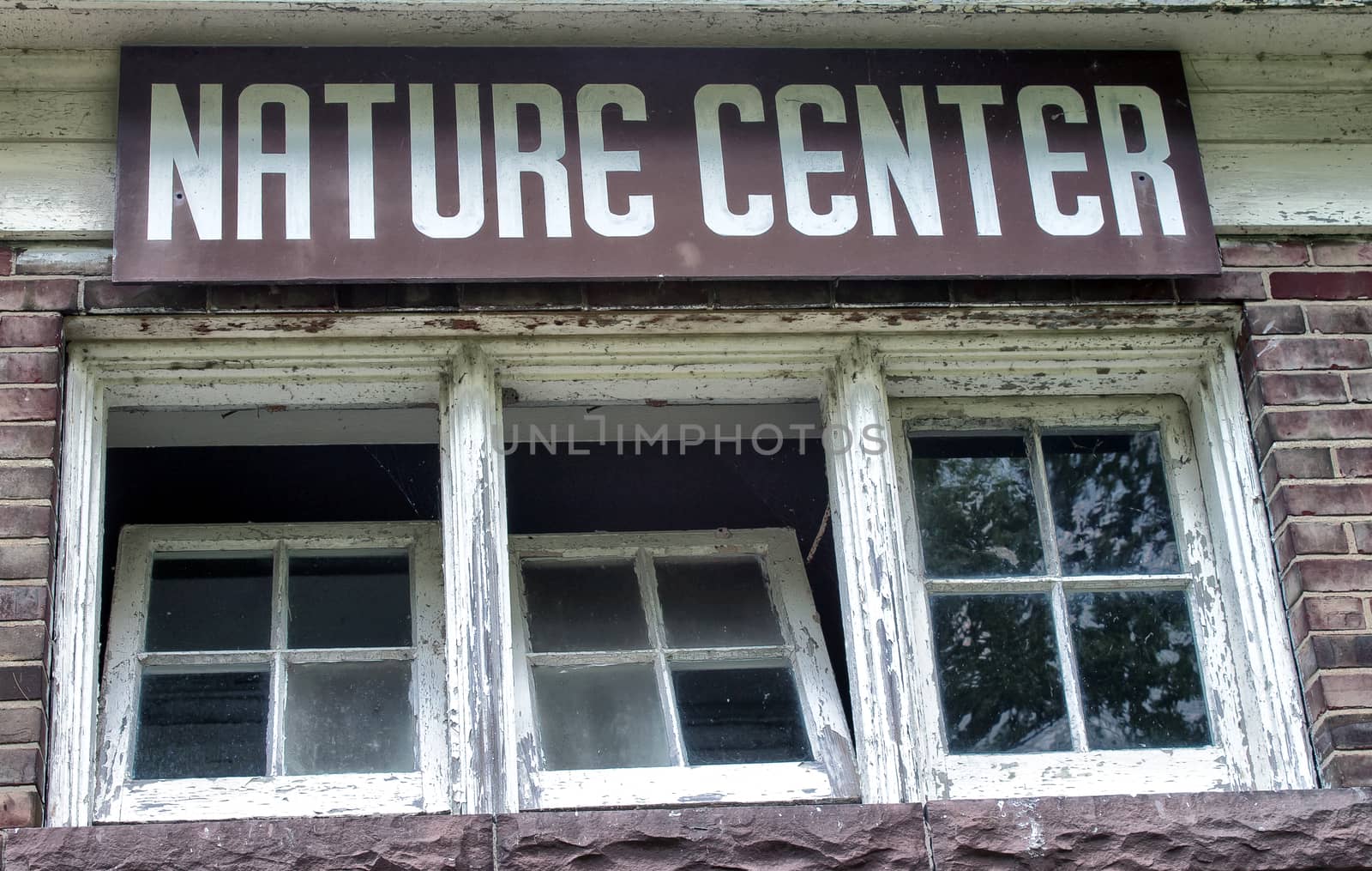 Nature center sign hangs over old style paned windows. 