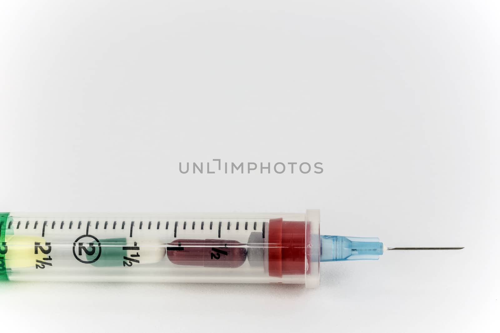 Intravenous syringe and needle filled with a dosage of colorful pill narcotics. 