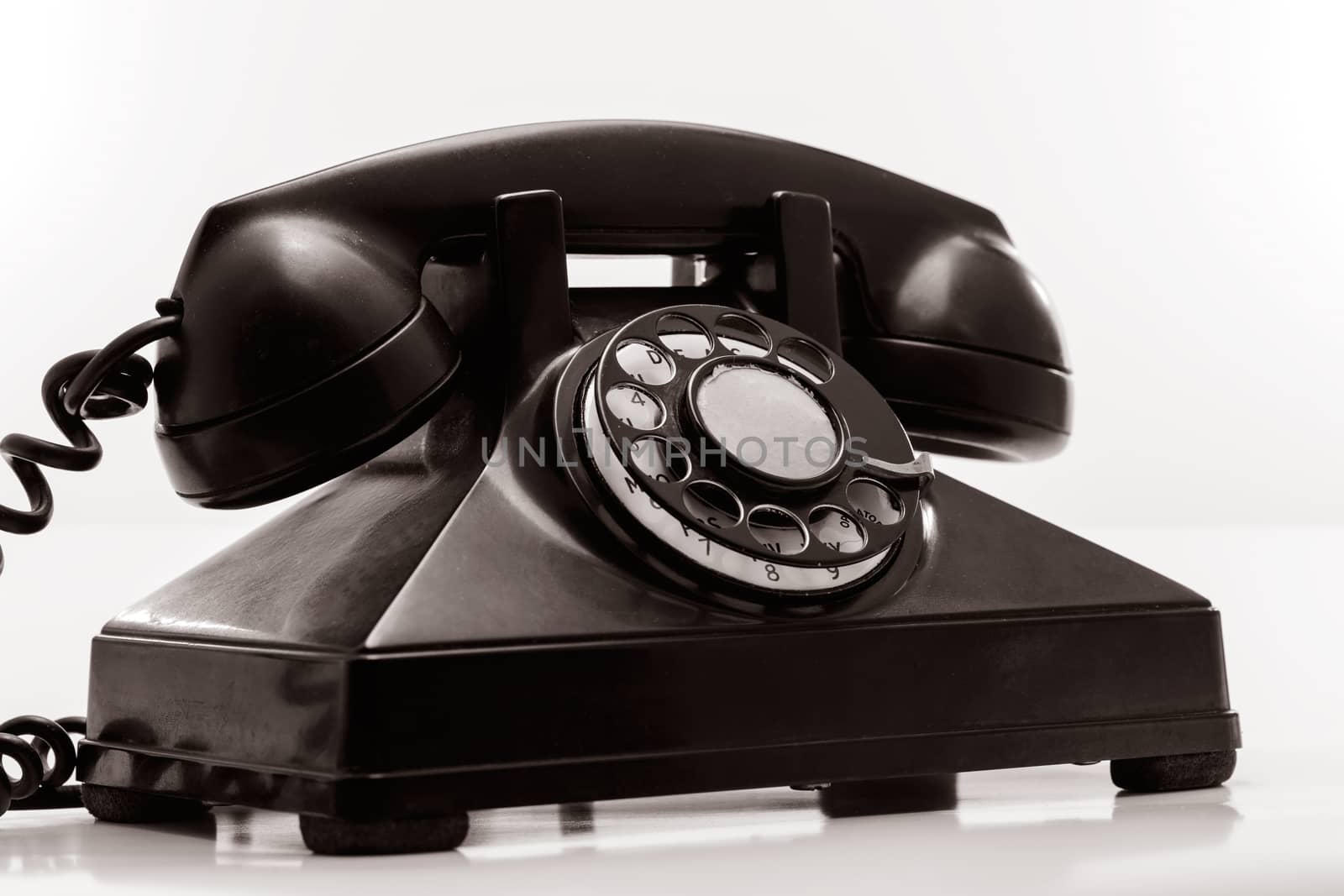 Black rotary dial phone on white. 