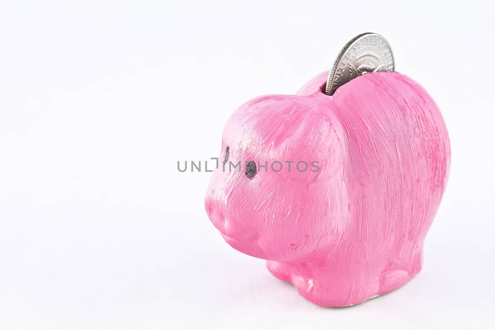 Hand-painted pink piggybank with an oversized coin sticking out. American silver half dollar.