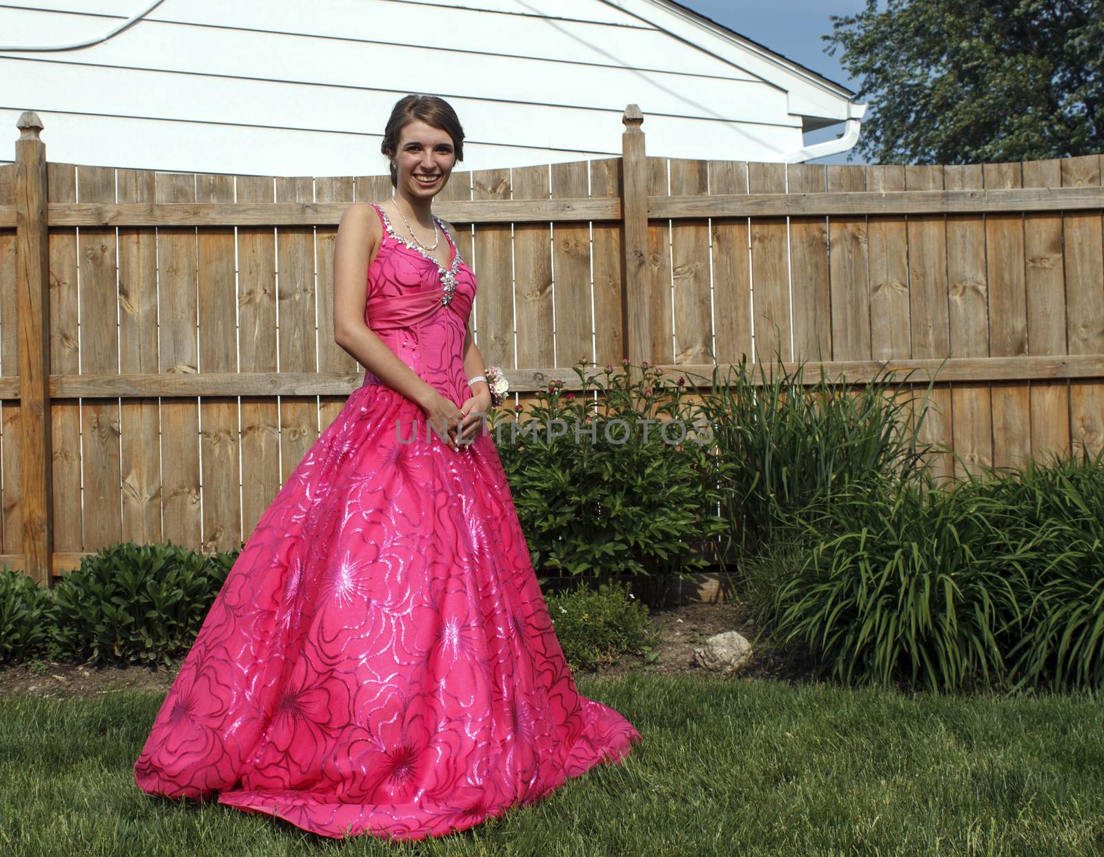Girl poses outside in her beautiful pink prom dress.