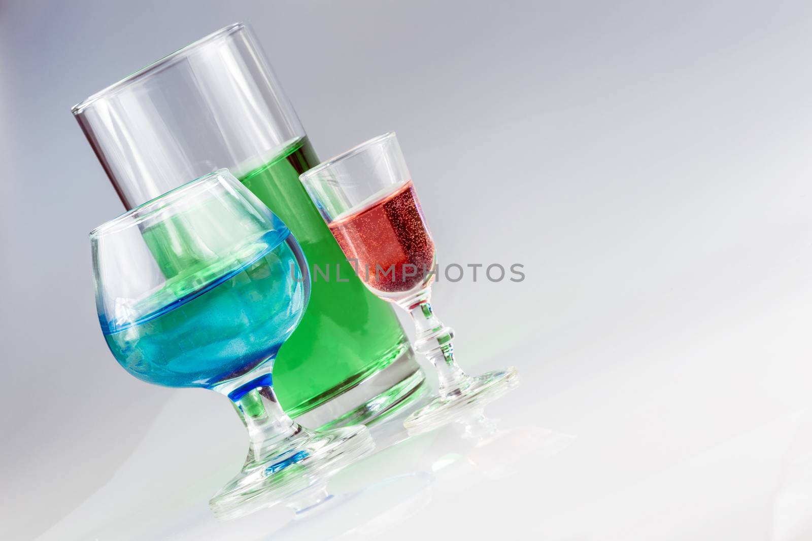 Three different style drinking glasses full of bright colorful liquid.