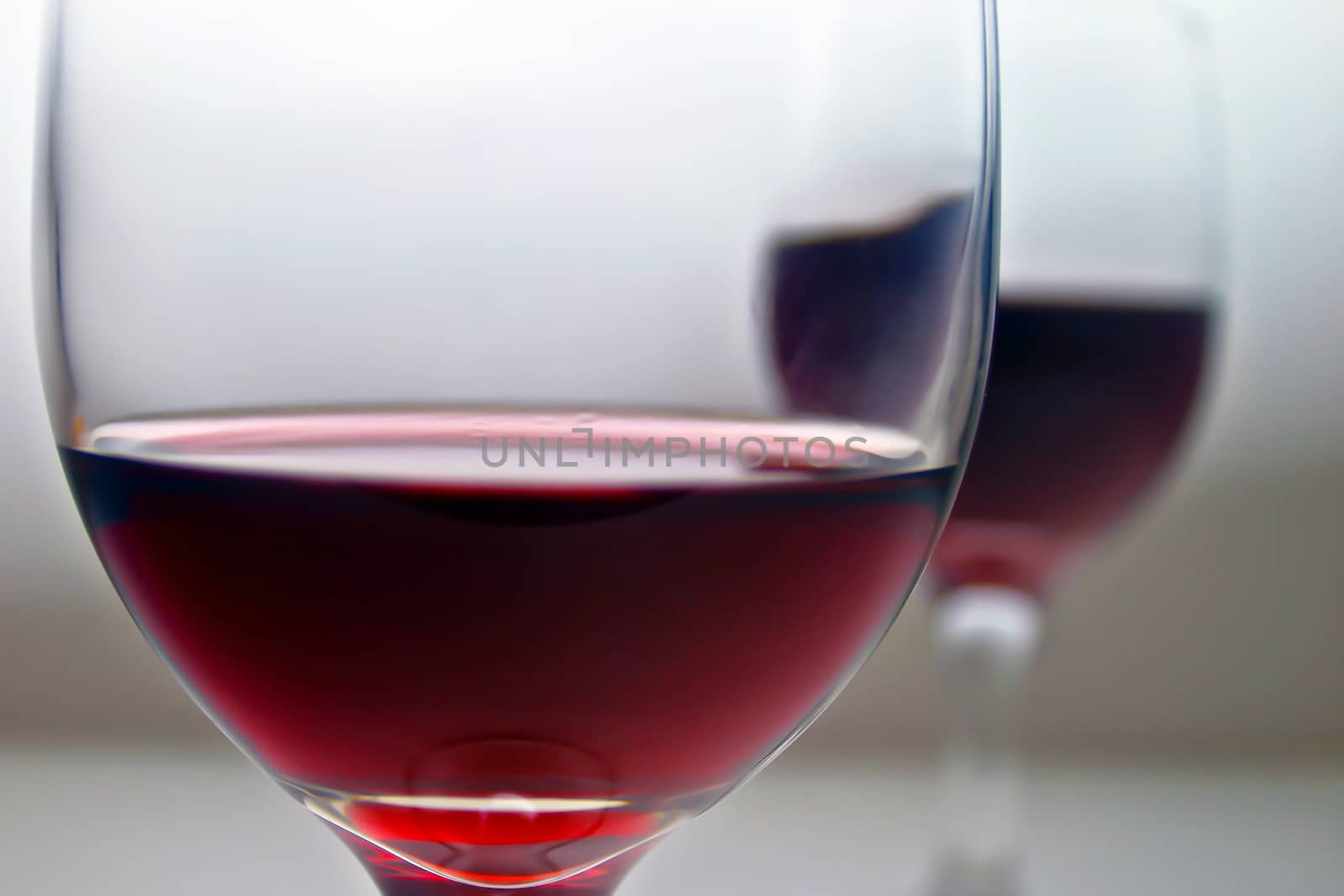 Closeup of two wine glass full of rich red wine. One in foreground, other in background. Varying amounts in each.