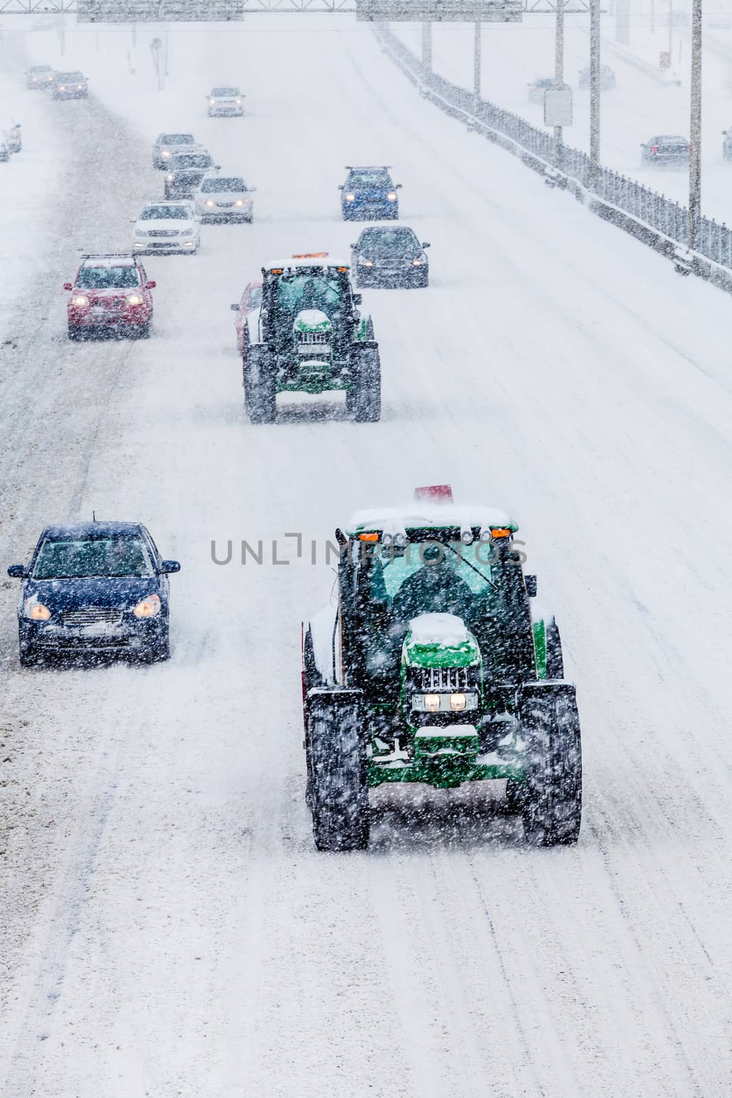 Two Snowplows and Cars on the Highway During a Snowstorm Winter Day