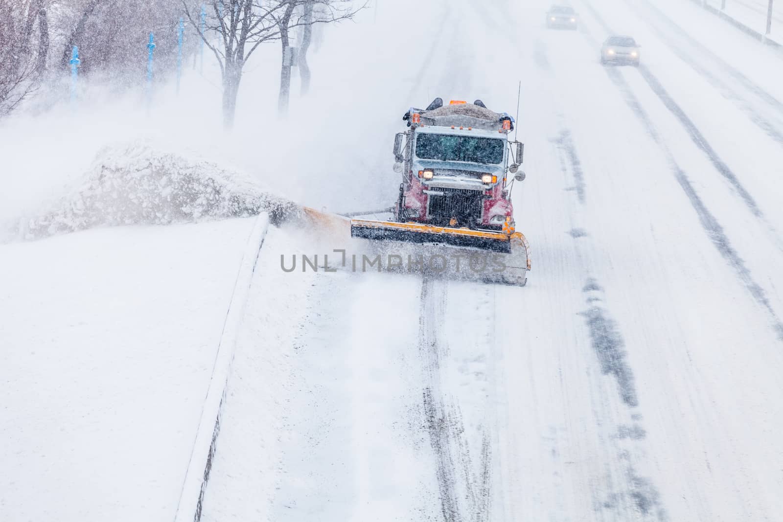 Snowplow Truck Removing the Snow from the Highway during a Cold Snowstorm Winter Day