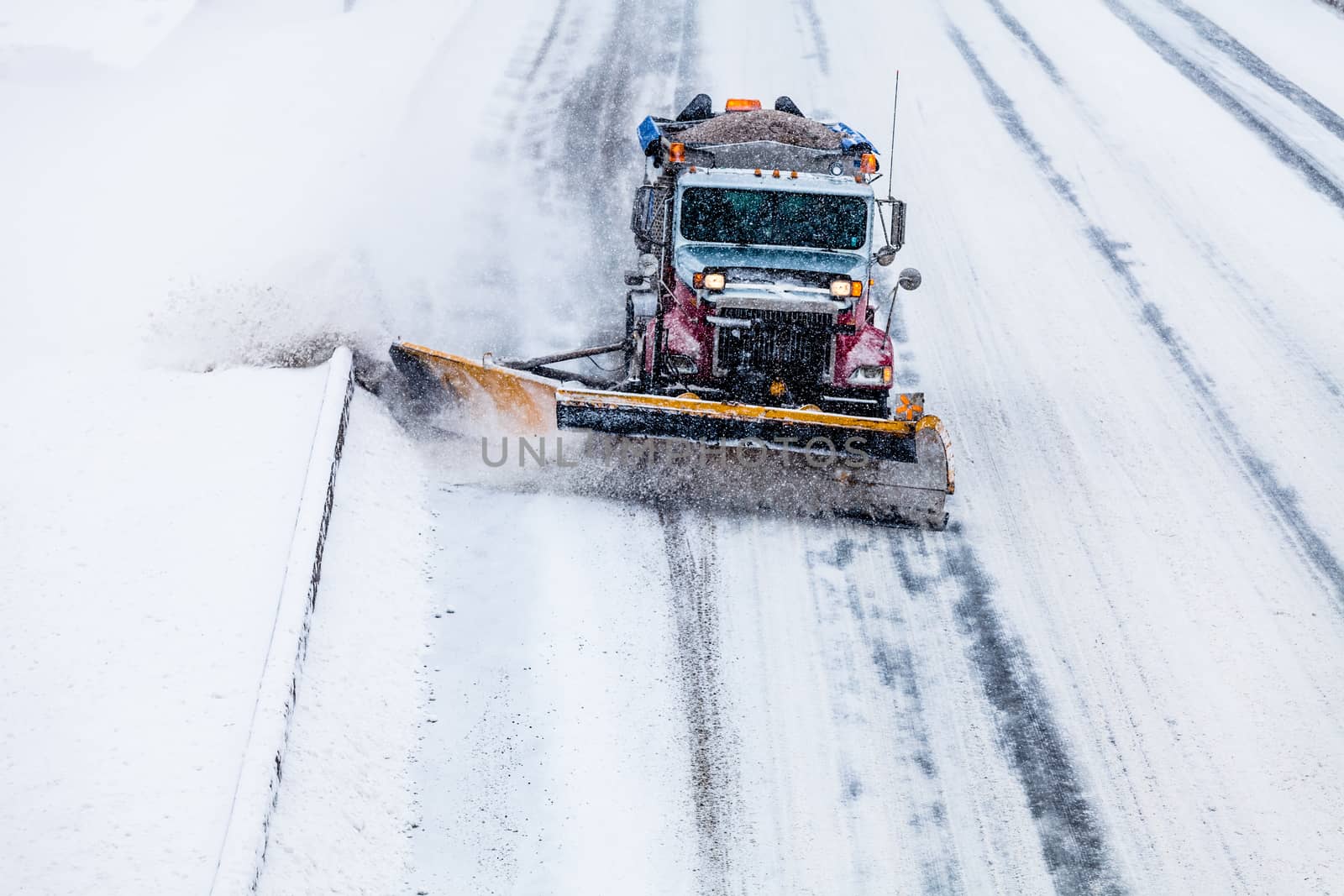 Snowplow removing the Snow from the Highway during a Snowstorm by aetb