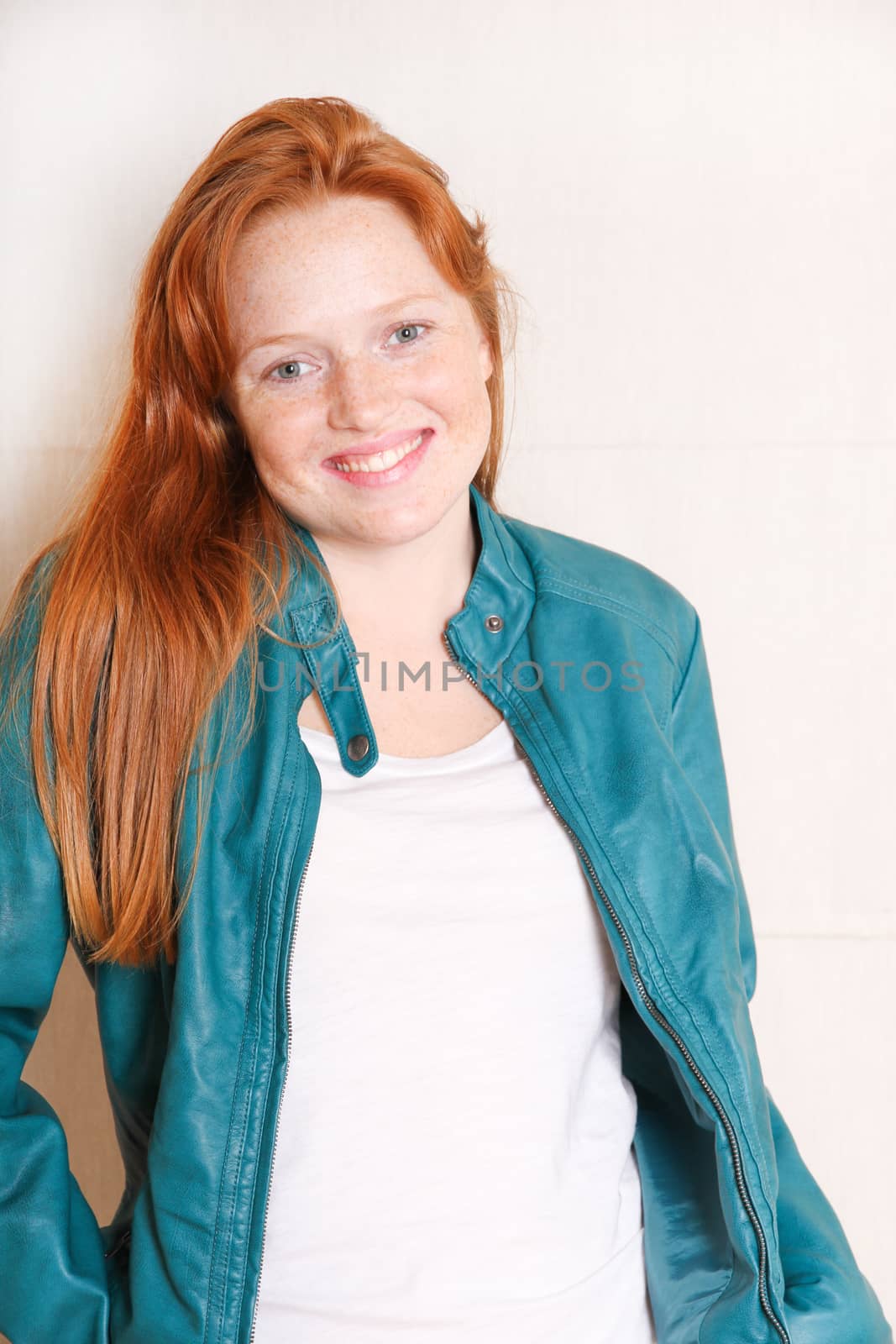 A attractive young, redhead woman with a green jacket.  
