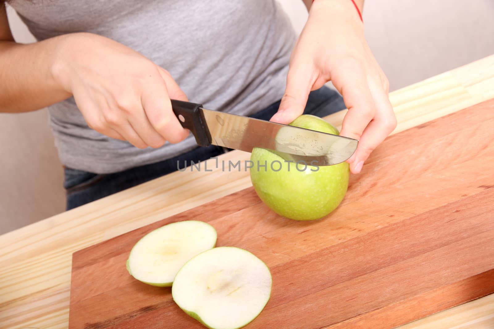 A young adult woman cutting a Apple in the kitchen.