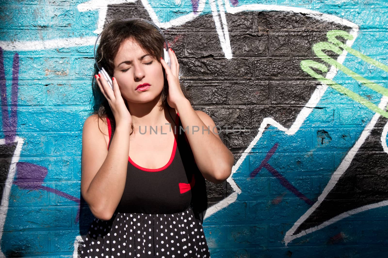 A vintage dressed girl listing to music in a urban environment.