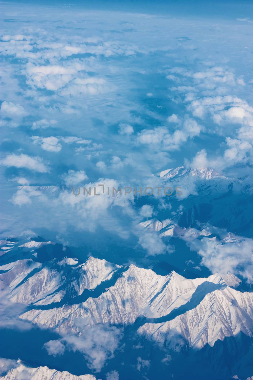 Top view of mountains with snow and clouds.