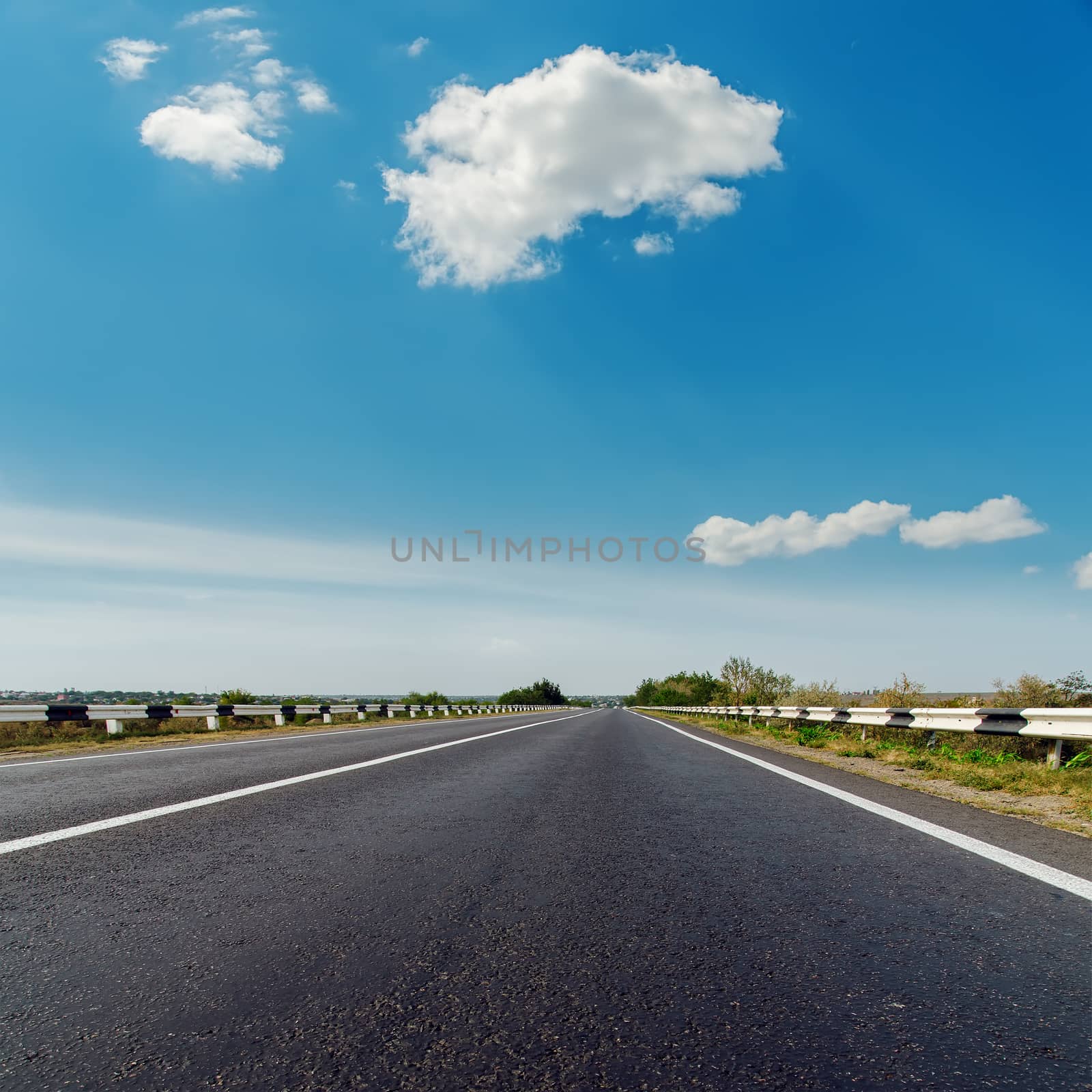 asphalt road to horizon under blue cloudy sky by mycola