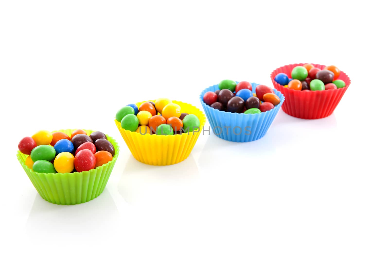 Cups with colorful candy over white background