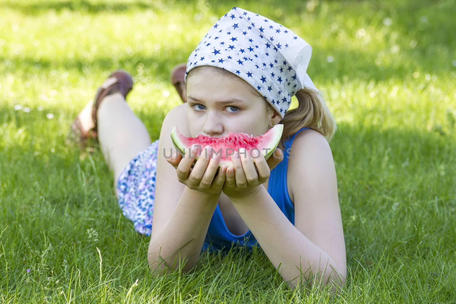 cute little girl eating watermelon on the grass by miradrozdowski