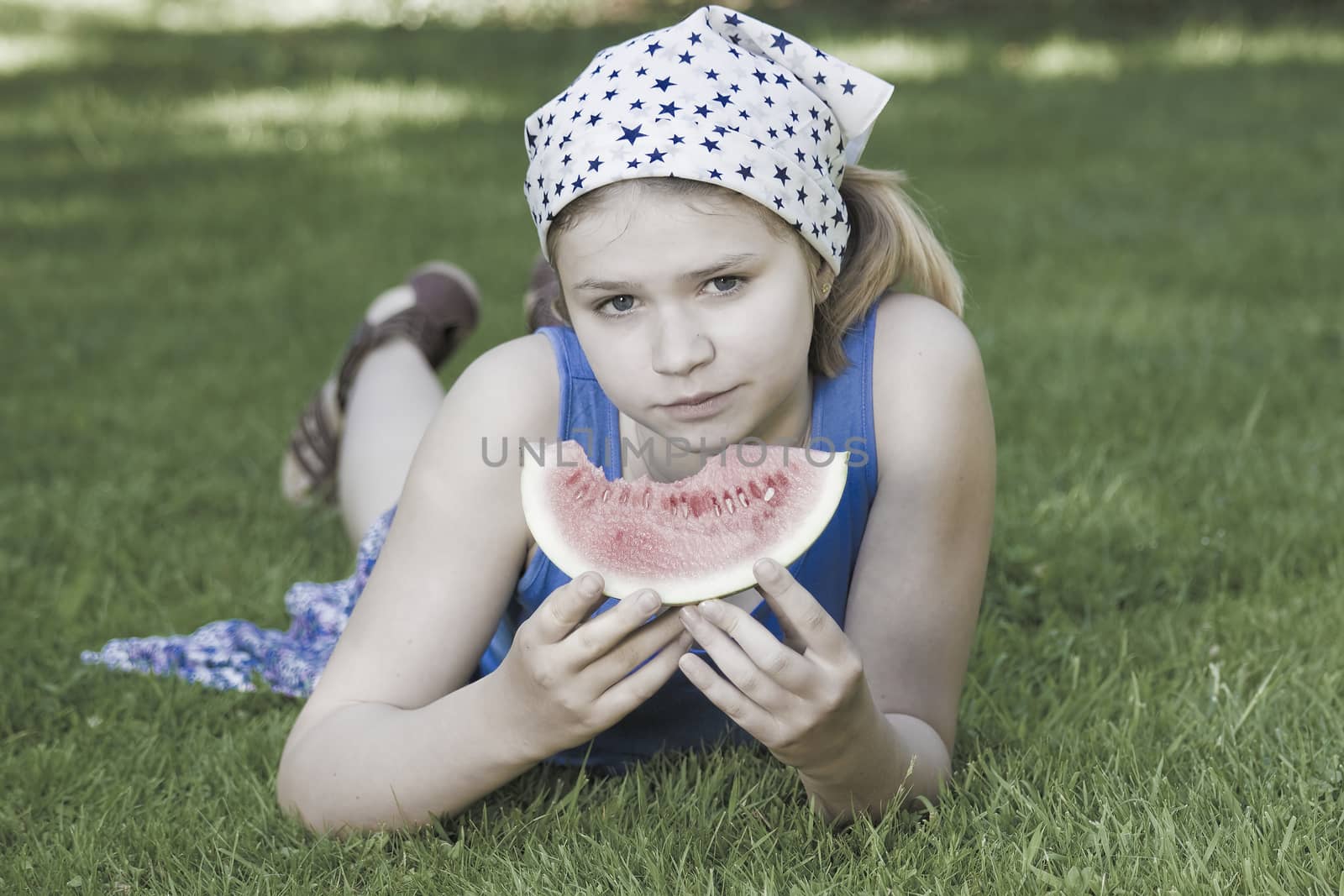 cute little girl eating watermelon on the grass by miradrozdowski