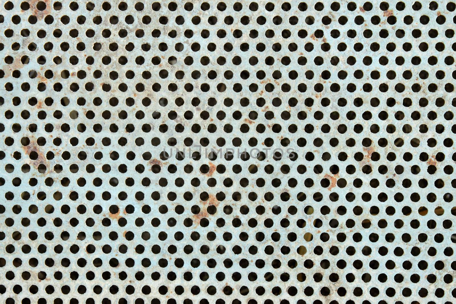 Old metal grate with round holes painted in light blue as a texture