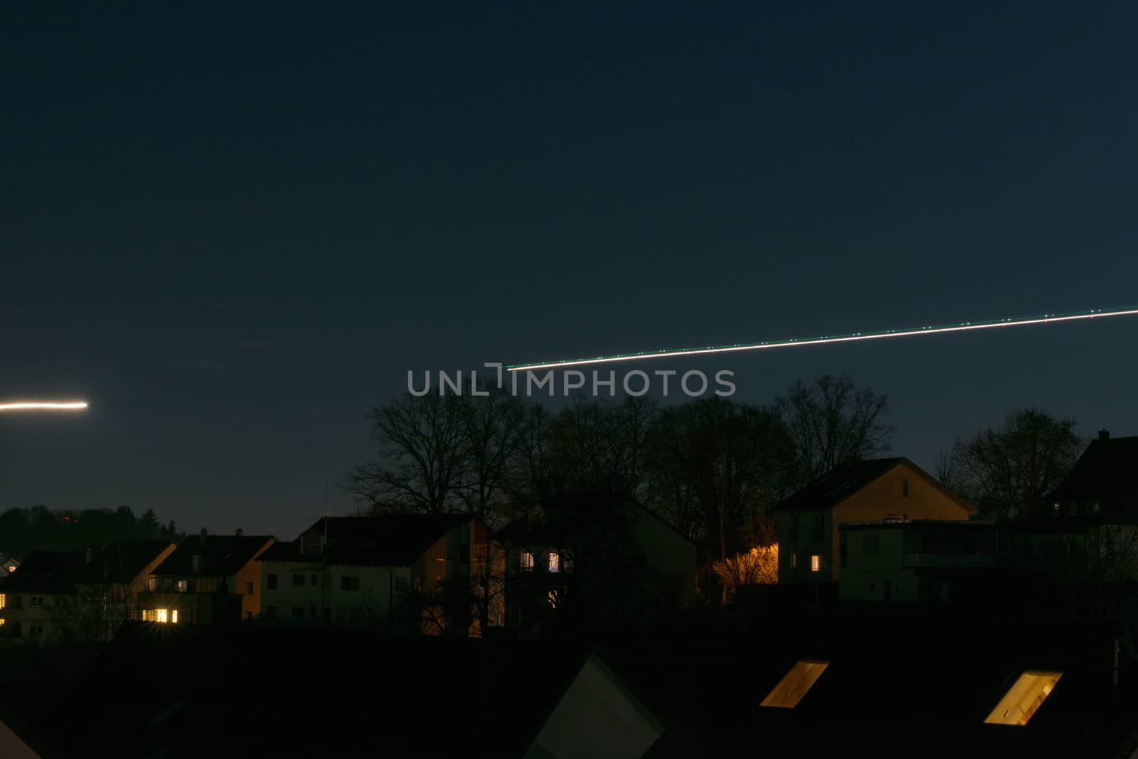 Jet airplanes are departing at night and leaving light traces, long exposure shot