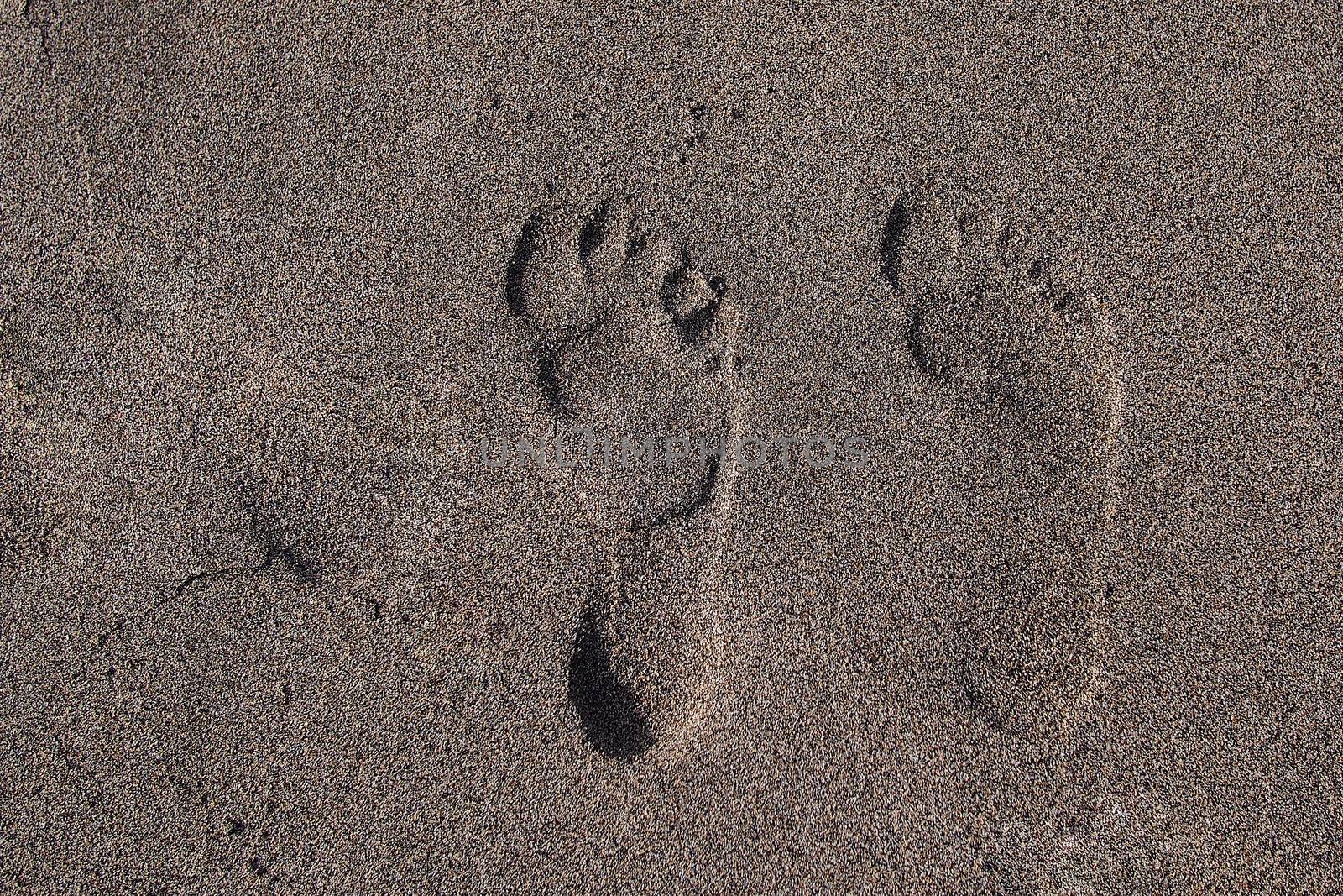 Two footprints in the sand, near the beach