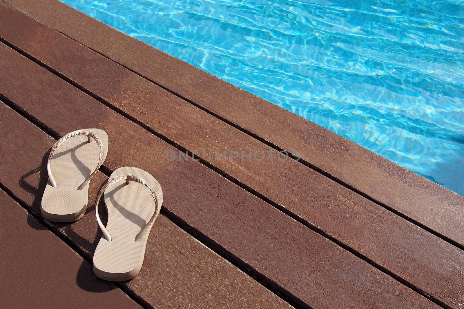 Flip flops by the swimming pool by stockyimages