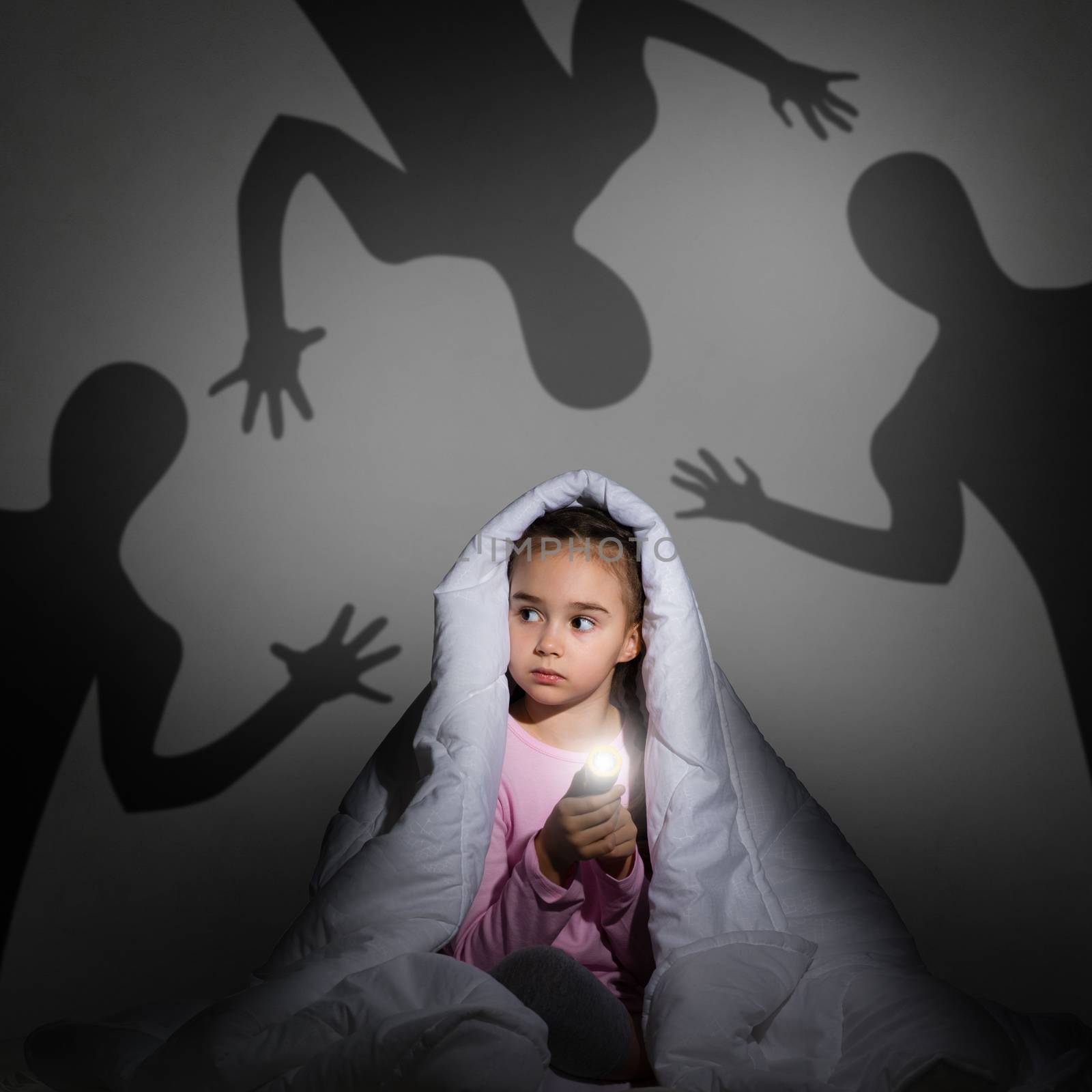 image of a girl under the covers with a flashlight the night afraid of ghosts