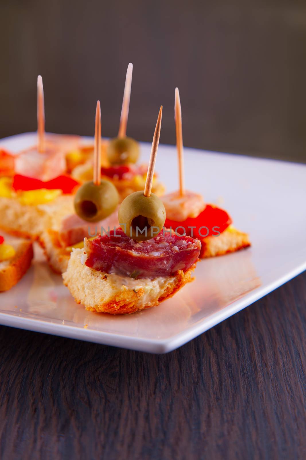 Appetizers with sausage and olives over white plate