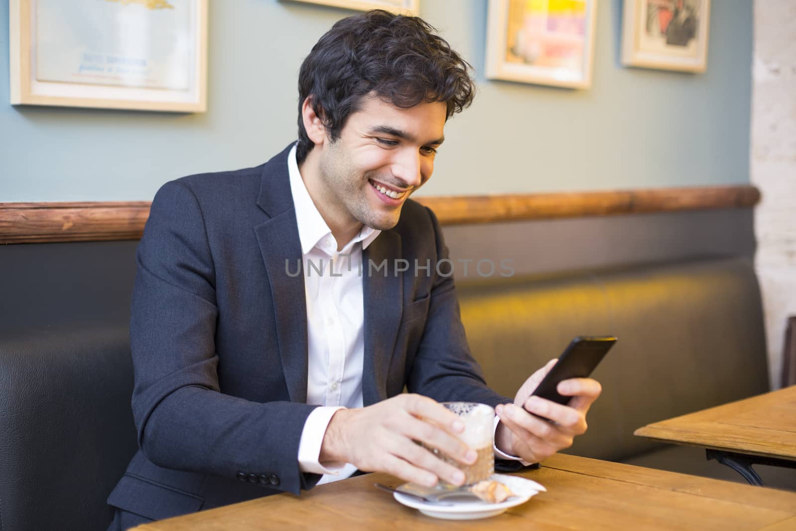 Handsome man using a cell phone in coffee bar by LDProd